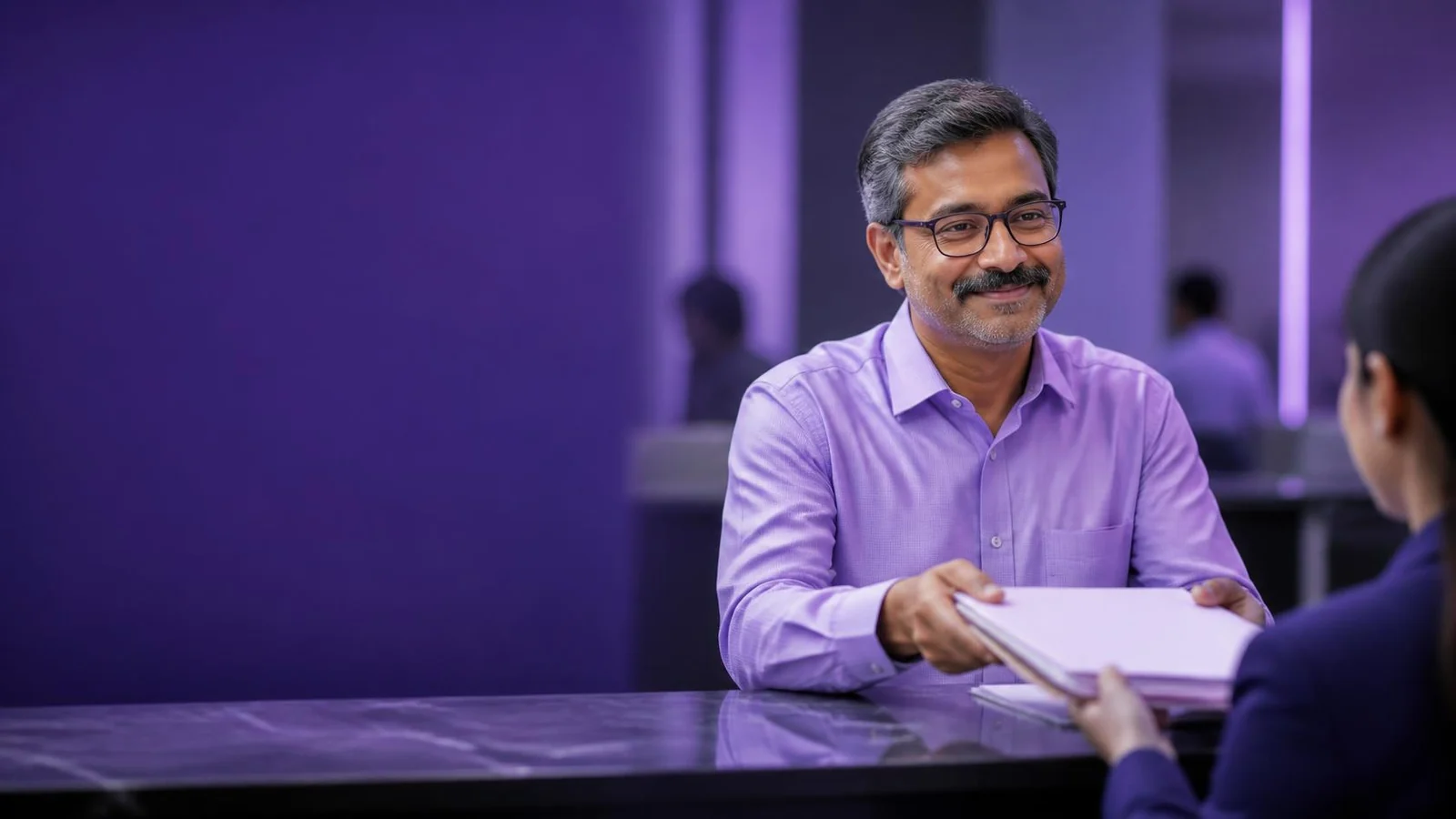 A man handing a folder of documents across a service counter